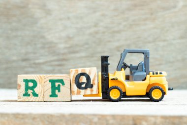 Oyuncak forklift harf bloğu Q 'yu tahta arkaplanda RFQ (tırnak için talep kısaltması) tamamlamak için tutar