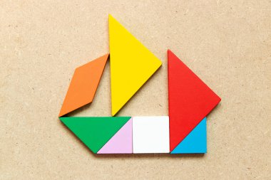 Ahşap zemin üzerinde yelkenli teknesi şeklindeki renk tangramı (Girişimci ya da iş kurma kavramı)