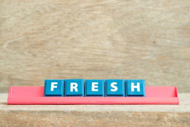 Döşeme alfabesi harfi. Ahşap zemin üzerinde kırmızı rafta taze bir kelime var.