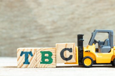 TBC (doğrulanacak ya da devam edecek kısaltması) sözcüğünün tamamlanması için C harfi forklift blok bloğunu tahta arkaplanda tut