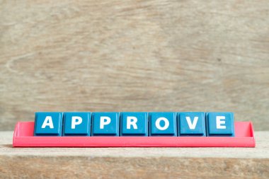 Ahşap arkaplanda kırmızı renk rafında kelime onaylı döşeme alfabesi harfi