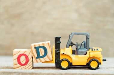 Toy forklift harf bloğu D 'yi ahşap arkaplan üzerinde OD (kısaltma overdraft) kelimesinin tamamlanması için tut