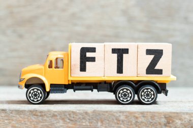 Oyuncak kamyonu tahta zemin üzerinde kelime FTZ (Serbest ticaret bölgesinin kısaltılmışı) harfli harf bloğu tutuyor