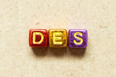 Tahta zemin üzerinde DES (Delivered Ex Ship 'in kısaltması) kelimesindeki metalik renk harf bloğu