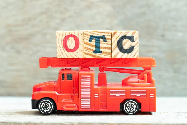 Fire ladder truck hold letter block in word OTC (Abbreviation of over the counter) on wood background