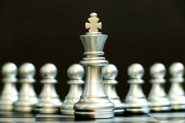 Gümüş papaz siyah arka planda gümüş piyon takımının önünde duruyor (Lider için kavram, eşsiz ya da seçkin)