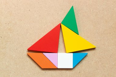 Ahşap zemin üzerinde yelkenli teknesi şeklindeki renk tangramı (Girişimci ya da iş kurma kavramı)