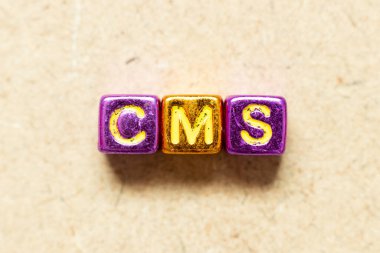Ahşap zemin üzerinde CMS (İçerik yönetim sisteminin kısaltması) kelimesindeki metalik renk alfabesi harf bloğu