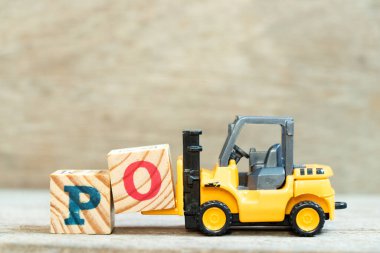 Ahşap arkaplan üzerindeki PO (satın alma emrinin kısaltılması) sözcüğünü tamamlamak için O harfi tutulan oyuncak forklift bloğu