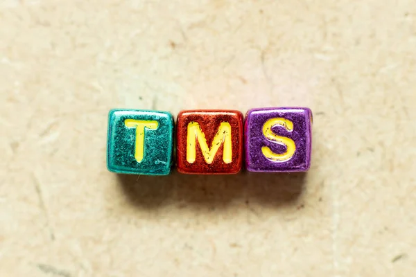 Tahta zemin üzerinde TMS (Taşımacılık yönetim sisteminin kısaltması veya Transkraniyal manyetik uyarı) kelimesindeki metalik renk harf bloğu