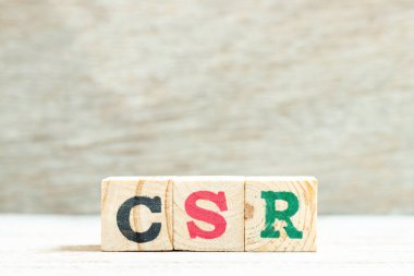 Tahta zemin üzerinde kelime CSR (kurumsal sosyal sorumluluğun kısaltılmışı) ile alfabe harfi engelleyici