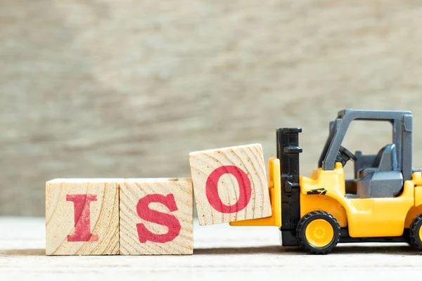 Oyuncak forklift ahşap arkaplan üzerindeki izo sözcüğünü tamamlamak için harf bloğunu tut