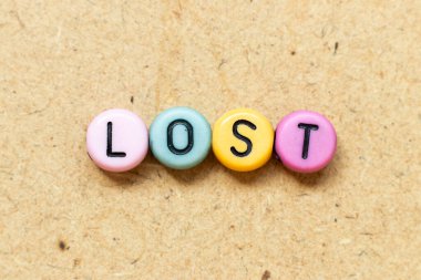 Yuvarlak renk boncuğu, ahşap arka planda kaybolmuş siyah harfle.