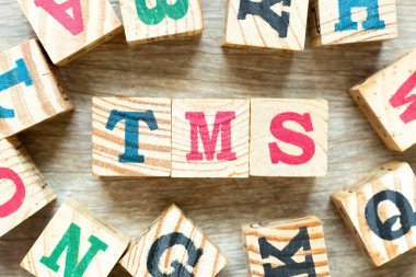 Kelime TMS ile alfabe harf bloğu (Taşımacılık yönetim sisteminin kısaltılmışı veya Transkraniyal manyetik uyarı) tahta arka planda başka bir