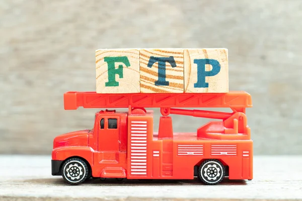 Fire ladder truck hold letter block in word FTP (Abbreviation of File Transfer Protocol) on wood background