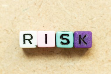 Tahta arkaplanda kelime riski içeren renk alfabesi harfi bloğu