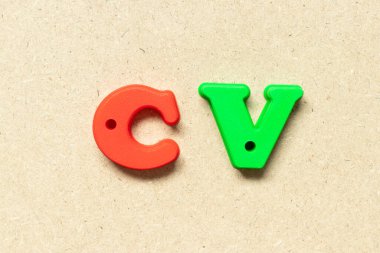 Ahşap arkaplan üzerindeki plastik alfabe harfi CV (müfredat vitae 'nin kısaltması)
