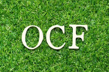 Alfabe harfi OCF (İşletme nakit akışının kısaltılmışı) yeşil çimen arka planında