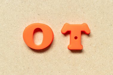 Ahşap arka planda plastik alfabe harfi OT (fazla mesai için kısaltma)