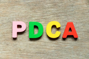 Ahşap arkaplan üzerinde kelime PDCA ile renk alfabesi harfi (planın kısaltması kontrol eylemi)