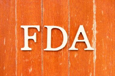 Gıda ve uyuşturucu yönetiminin kısaltması olan kelime FDA ile alfabe harfleri eski kırmızı tahta arka plan üzerine