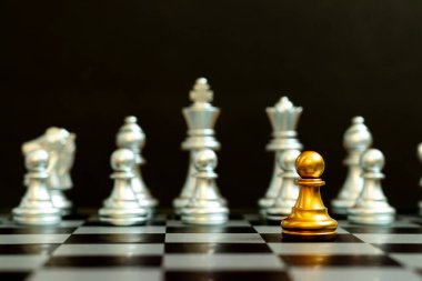 Satranç oyununda altın piyon siyah zemin üzerinde diğer gümüş takım ile birlikte (Şirket stratejisi, iş zaferi veya karar kavramı)
