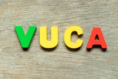 Kelime VUCA ile renk alfabesi harfi (ahşap arkaplan üzerinde uçuculuğun kısaltması, belirsizlik, karmaşıklık ve belirsizlik)