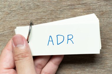 Adam ahşap zemin üzerinde el yazısı ADR (ters uyuşturucu reaksiyonunun kısaltması) ile flash kartı tutun
