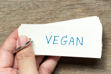 Adam, tahta arka planda el yazısı vegan olan flaş kartı tut.