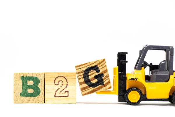 玩具フォークリフト木の背景に単語B2G 政府へのビジネスの略語 を完了するために文字ブロックGを保持します — ストック写真