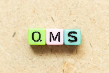 Tahta zemin üzerinde QMS (kalite yönetim sisteminin kısaltması) ile renk alfabesi harf bloğu