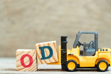 Toy forklift harf bloğu D 'yi ahşap arkaplan üzerinde OD (kısaltma overdraft) kelimesinin tamamlanması için tut