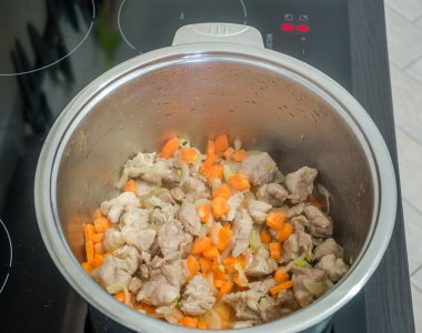 Paslanmaz çelik demir potu soğan ve havuç etli pilav pişirme için hazırlar bir indüksiyon Ocak