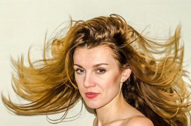 Genç güzel kız model ile uzun saçları hafif bir arka plan üzerinde olumlu duygular ile gülümseyerek poz