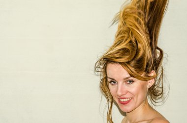 Genç güzel kız model ile uzun saçları hafif bir arka plan üzerinde olumlu duygular ile gülümseyerek poz