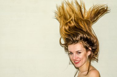 Genç güzel kız model ile uzun saçları hafif bir arka plan üzerinde olumlu duygular ile gülümseyerek poz