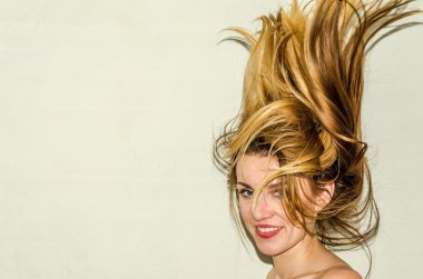 Genç güzel kız model ile uzun saçları hafif bir arka plan üzerinde olumlu duygular ile gülümseyerek poz