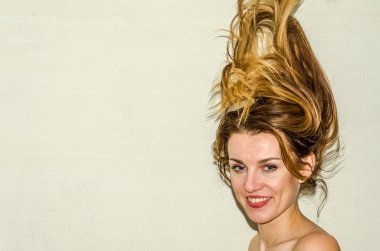 Genç güzel kız model ile uzun saçları hafif bir arka plan üzerinde olumlu duygular ile gülümseyerek poz