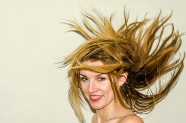 Genç güzel kız model ile uzun saçları hafif bir arka plan üzerinde olumlu duygular ile gülümseyerek poz