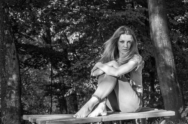 Όμορφη σέξι κοπέλα ξανθιά μοντέλο με μακριά ξανθά μαλλιά στο τζιν και μπουφάν που παρουσιάζουν στο δάσος ανάμεσα στα δέντρα και βλάστηση — Φωτογραφία Αρχείου