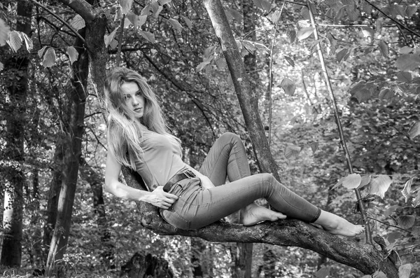 长长的金发，穿着牛仔裤和夹克在树林之中的树木和植被构成年轻美丽性感的女孩金发模型 — 图库照片