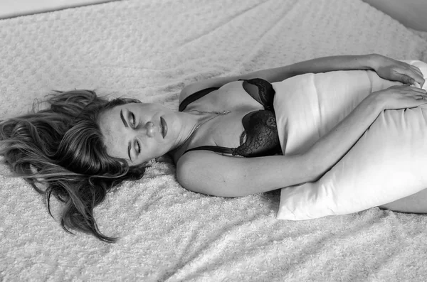 Młody uroczy sexy dziewczyna z długimi włosami pozowanie erotycznie w łóżku w bieliźnie rano po przebudzeniu przytulanie jej poduszkę — Zdjęcie stockowe