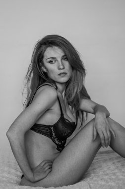 Uzun saçlı güzel seksi iç çamaşırı çarşaf üzerinde erotik poz ve ışık ışık arka plan üzerinde oturan genç büyüleyici kadın