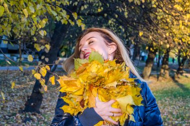 Güzel genç kız mutlu bir kadın gülümseyerek ve sarı akçaağaç tutan sonbahar Park'ta yürüyordunuz bırakır