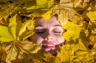 Güzel genç kız mutlu bir kadın gülümseyerek ve sarı akçaağaç tutan sonbahar Park'ta yürüyordunuz bırakır