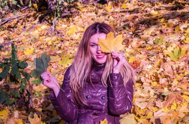 Güzel genç kız mutlu bir kadın gülümseyerek ve sarı akçaağaç tutan sonbahar Park'ta yürüyordunuz bırakır