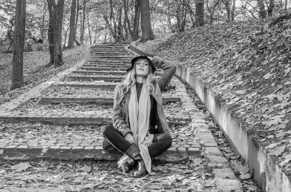 La bella ragazza una donna felice sorridente e con in mano una foglia d'acero gialla che cammina nel parco autunnale — Foto Stock