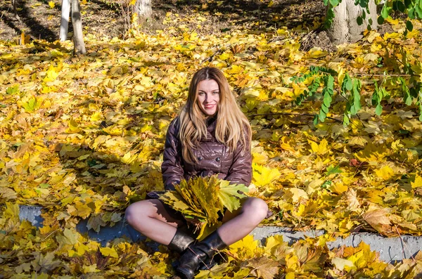Piękna młoda dziewczyna kobieta szczęśliwy uśmiechający się i przytrzymując żółty klon pozostawia spaceru w parku jesień — Zdjęcie stockowe
