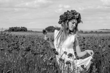 Kafasında bir çelenk ile haşhaş alanındaki beyaz elbiseli uzun saçlı genç güzel mutlu kız