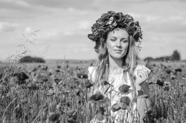 Kafasında bir çelenk ile haşhaş alanındaki beyaz elbiseli uzun saçlı genç güzel mutlu kız